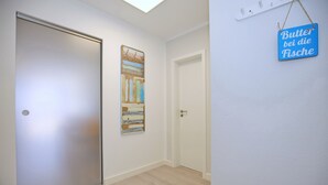 Un pasillo con una puerta cerrada, una obra de arte colgada en la pared y un cartel que dice "Butter bei die Fische".