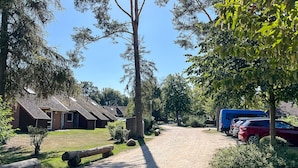 Een camping met accommodaties, een grindpad en geparkeerde voertuigen.