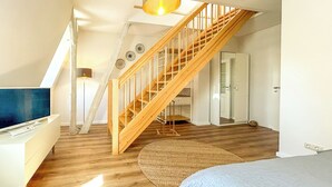 Een ruime kamer met een houten trap, een groot bed, een bureau en een televisie.