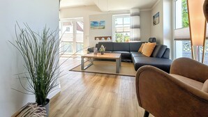 A modern living room with a sofa, coffee table, and a potted plant. - Landidyll Wohnung 03 in Elmenhorst (Elmenhorst)