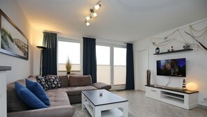 Una sala de estar moderna con un sofá, una mesa de centro, televisor y elementos decorativos.