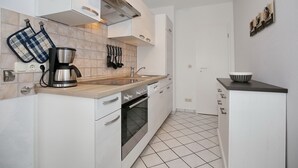 Una cocina moderna con gabinetes blancos, una cafetera de acero inoxidable y un salpicadero de azulejos.