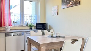 Cuina compacta amb zona de menjador, que inclou microones, rentaplat i una petita planta en test.