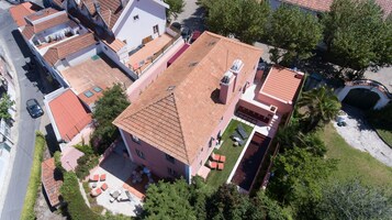 Vista aérea de un edificio residencial con techo de tejas, un pequeño patio con mobiliario exterior y una zona ajardinada.