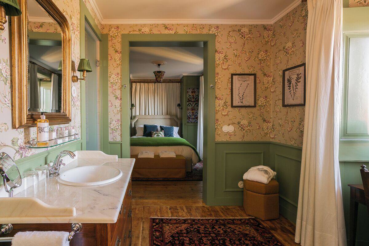 A bathroom with a marble sink, a large mirror, and a green wall.