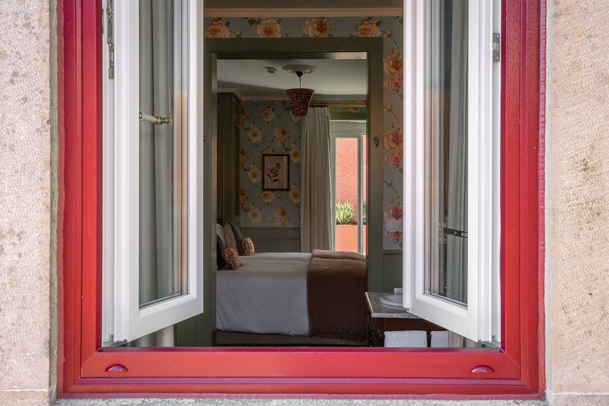A bedroom with a bed, a window, and a view of the outside.