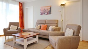 Un salon comprenant un canapé, deux fauteuils, une table basse et un tableau accroché au mur.