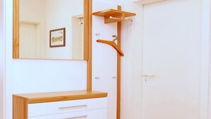 Une pièce avec une coiffeuse en bois, un miroir, une porte et un petit tapis.