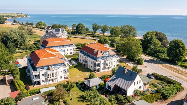 Een woongebied aan de kust met meerdere huizen, een helder uitzicht op zee en een verzorgd gazon.