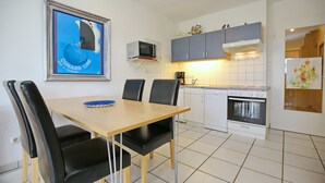 Una cocina moderna con una mesa de comedor y sillas, un microondas, armarios y una estufa.