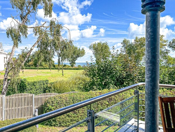Un parc avec une rambarde en métal, des arbres et une vue sur la mer.