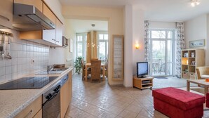 Una cocina moderna con comedor, televisor y un otoman rojo.