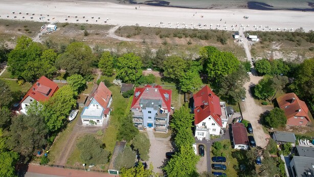 Vista aérea de una zona residencial costera con casas, una playa y cielo despejado.