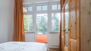 Un dormitorio con cama, ventanas amplias y armario de madera.