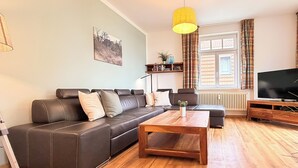 A living room with a sofa, coffee table, and TV. - Villa Triton Wohnung 03 (Ostseebad Boltenhagen)