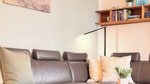 A brown leather sofa with cushions, a white vase with a plant, and a wooden coffee table. - Villa Triton Wohnung 03 (Ostseebad Boltenhagen)