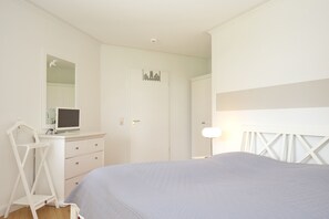 Un dormitorio con una cama, un escritorio con silla, un aparador y un armario.