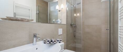 A modern bathroom with a white sink, toilet, and glass-enclosed shower.