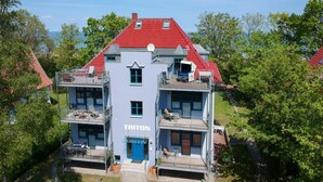 Ein mehrstöckiges Gebäude mit rotem Dach und blauer Eingangstür.
