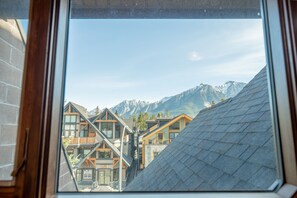Uitzicht op een bergketen door een raam, met gebouwen op de voorgrond.