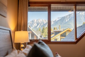 Ein Schlafzimmer mit großem Fenster und Blick auf eine Berglandschaft.
