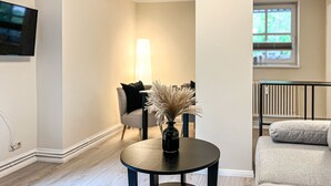 A modern living room with a round table, a sofa, and a TV mounted on the wall. - Villa Triton Wohnung 08 (Ostseebad Boltenhagen)