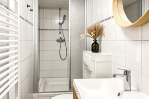 A modern bathroom with a shower, a sink, and a mirror.