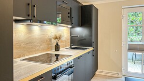 A modern kitchen with dark cabinetry, a wooden countertop, and a built-in oven. - Villa Triton Wohnung 08 (Ostseebad Boltenhagen)