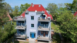 A multi-story building with a red roof and a blue entrance. - Villa Triton Wohnung 08 (Ostseebad Boltenhagen)