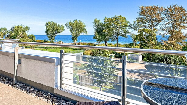 Een balkon met uitzicht op zee, metalen hekwerk en een fontein.