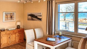 Een eethoek met een houten tafel en stoelen, een kast en kunst aan de muur.