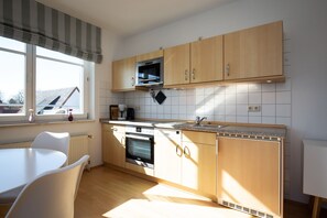 Eine moderne Küche mit Holzausstattung, einem eingebauten Ofen und einem Fenster für natürliches Licht.