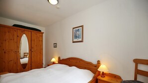 Une chambre à coucher avec un lit en bois, deux tables de chevet avec des lampes, une armoire en bois et un tableau encadré au mur.