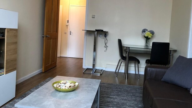 Een woonkamer met een bank, een salontafel en een eethoek met een tafel en stoelen.