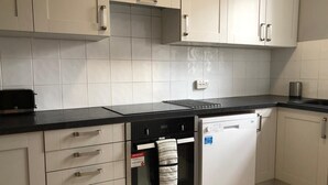 Een keuken met witte kastjes, een zwart aanrecht, een inbouwoven en een afwasschaal.