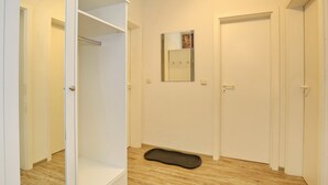 Una habitación con piso de madera, un tapete negro, un espejo y puertas blancas.