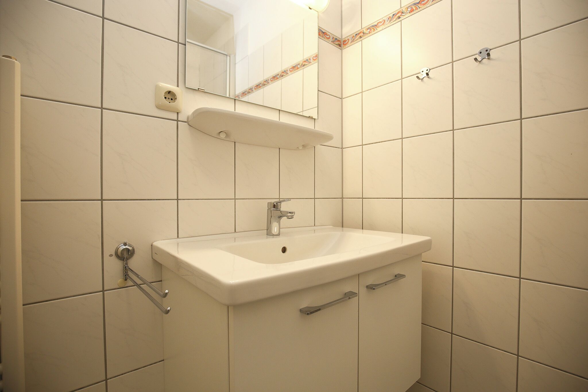 A bathroom with a white sink, a mirror, and a towel rack.