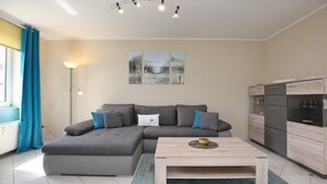 En moderne stue med en hjørnesofa, et træbord og et billede på væggen.