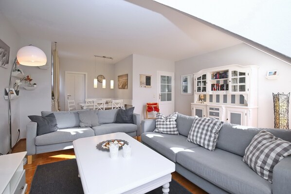 Ein modernes Wohnzimmer mit zwei grauen Sofas, einem weißen Couchtisch und einem Bücherregal.