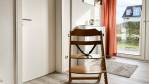 Een houten stoel met een hoofdsteun in een kamer met een schuifdeur die uitkomt op een tuin.