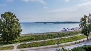 Eine Küstenansicht mit Strand, einer Seebrücke und einem Radfahrer auf einem Weg.