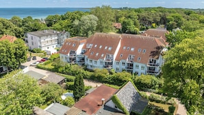 A residential area with a row of houses featuring red-tiled roofs and a view of the sea. - Likedeeler Wohnung 06 (Ostseebad Boltenhagen)