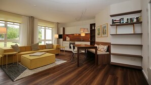 A modern living room with a sofa, a dining table, and a kitchen area. - Likedeeler Wohnung 06 (Ostseebad Boltenhagen)