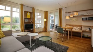 En moderne stue med sofa, fjernsyn og spiseplads.