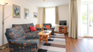 A living room with a sofa, a coffee table, a TV, and a lamp. - Sünnslag Wohnung 144 (Ostseebad Boltenhagen)