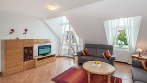 Una sala de estar moderna con sofá, televisor y mueble de madera.
