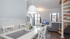 En moderne stue med spiseplads, trappe og fjernsyn.