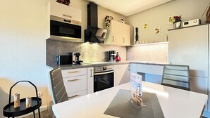 Una cocina moderna con armarios blancos, encimera negra y un comedor con mesa y sillas blancas.