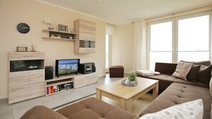 Ein modernes Wohnzimmer mit Flachbildfernseher, Holzbögen, einem Couchtisch und einem braunen Sofa.
