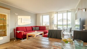 A modern living room with a red sofa, wooden coffee table, and a glass pitcher of water. - Sünnslag Wohnung 127 (Ostseebad Boltenhagen)